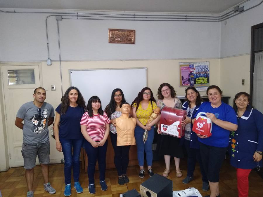 Grupo de asistentes de la educación con maniquíes y el kit cardioprotegido