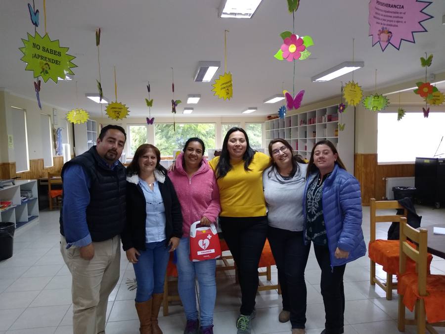 Grupo de docentes con un desfibrilador externo automático al terminar el curso